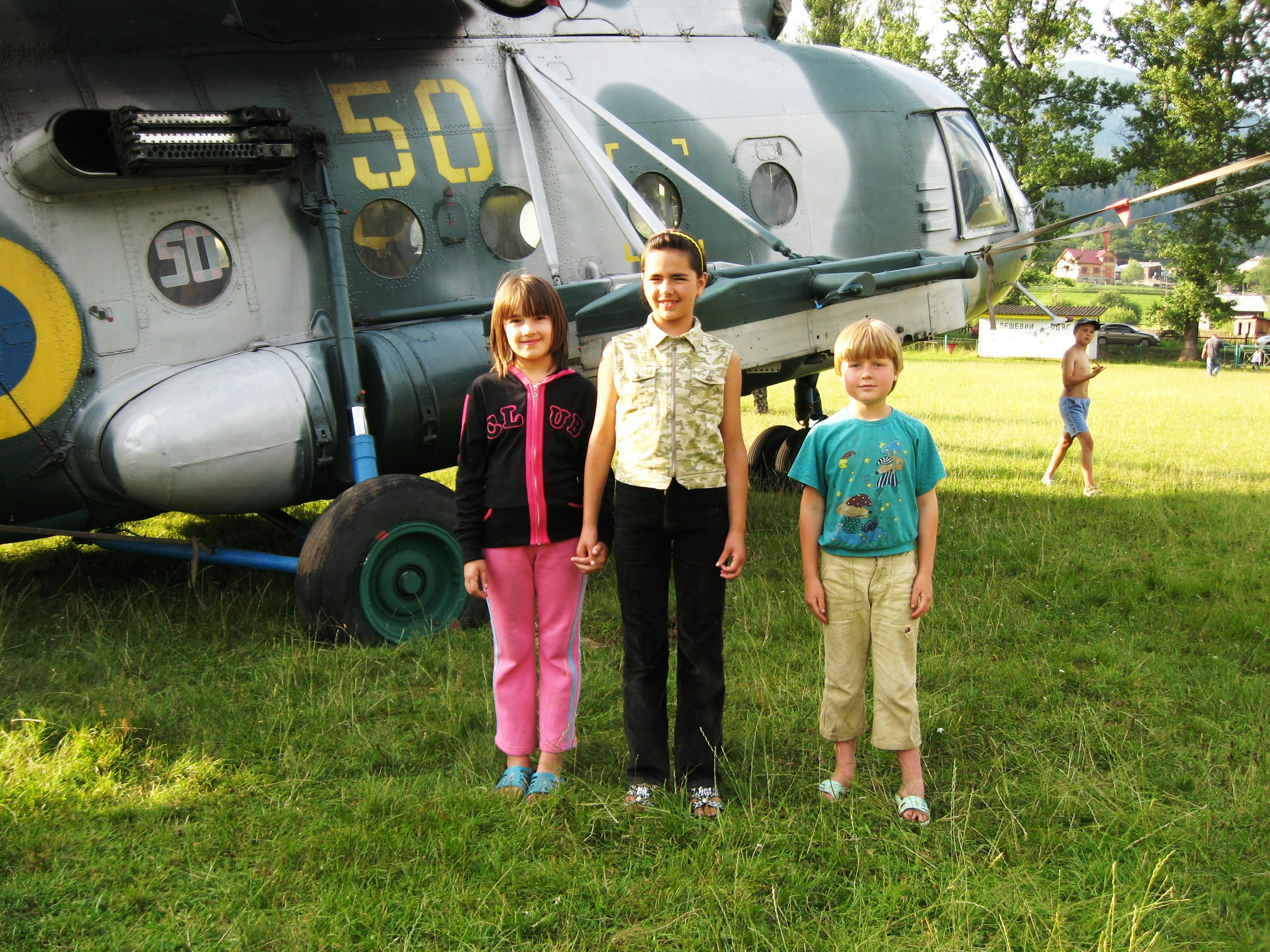three children standing in front of a helicopter