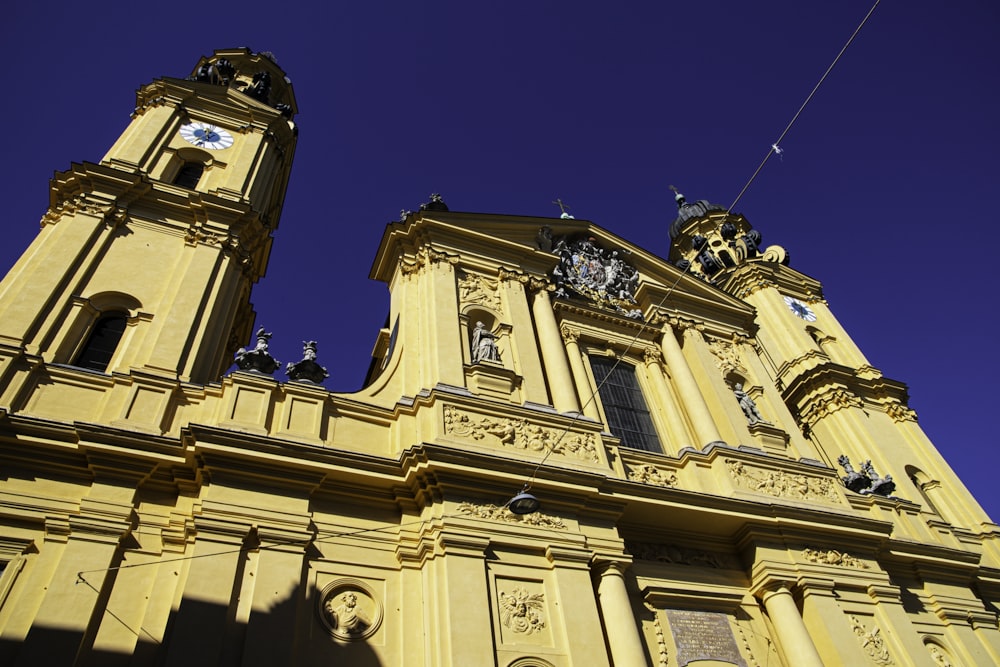 a tall yellow building with two clocks on each of it's sides