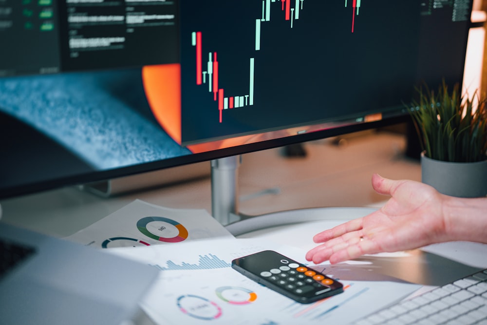 une personne pointant une calculatrice sur un bureau