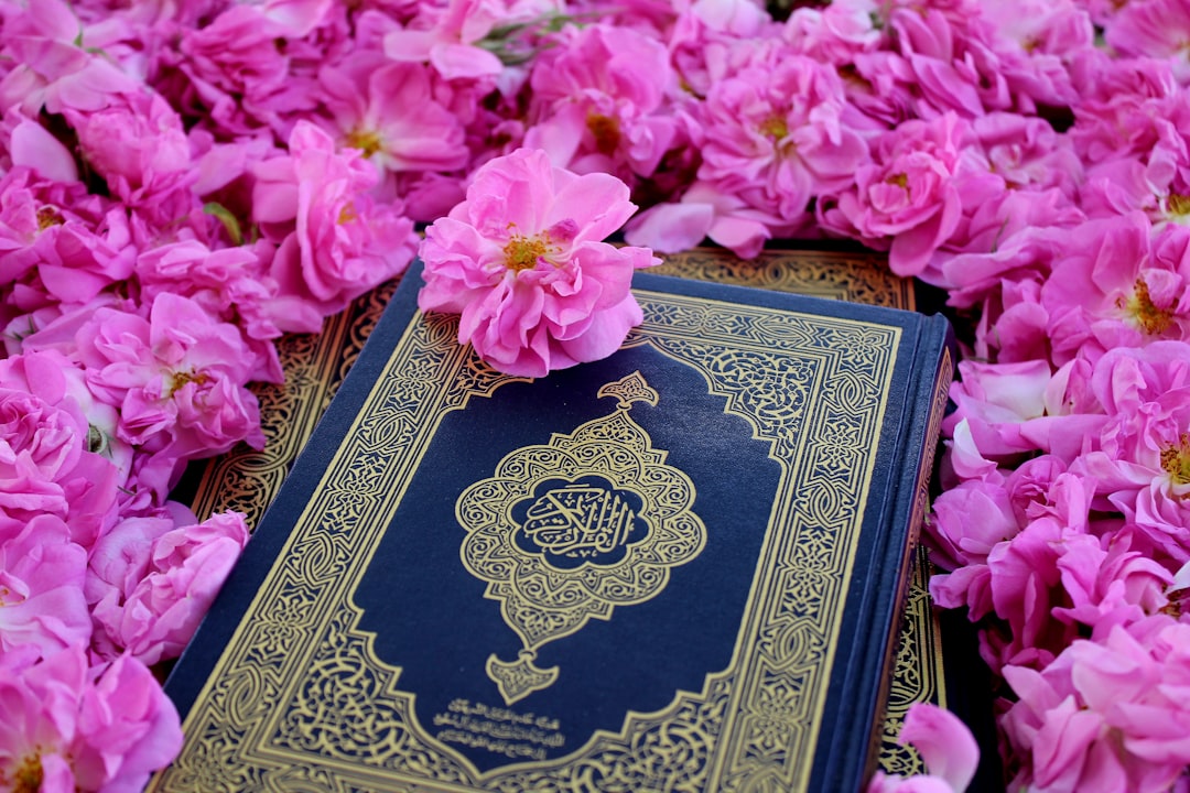 a blue and gold book surrounded by pink flowers