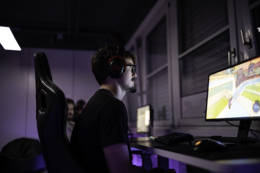 a man sitting in front of a computer with headphones on