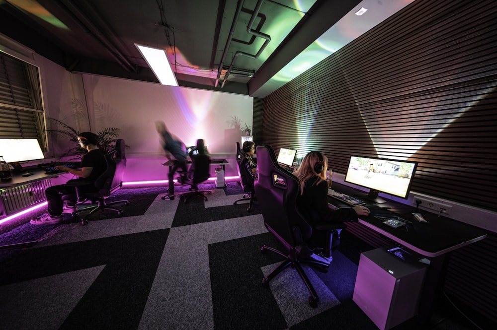 a group of people sitting around a computer desk