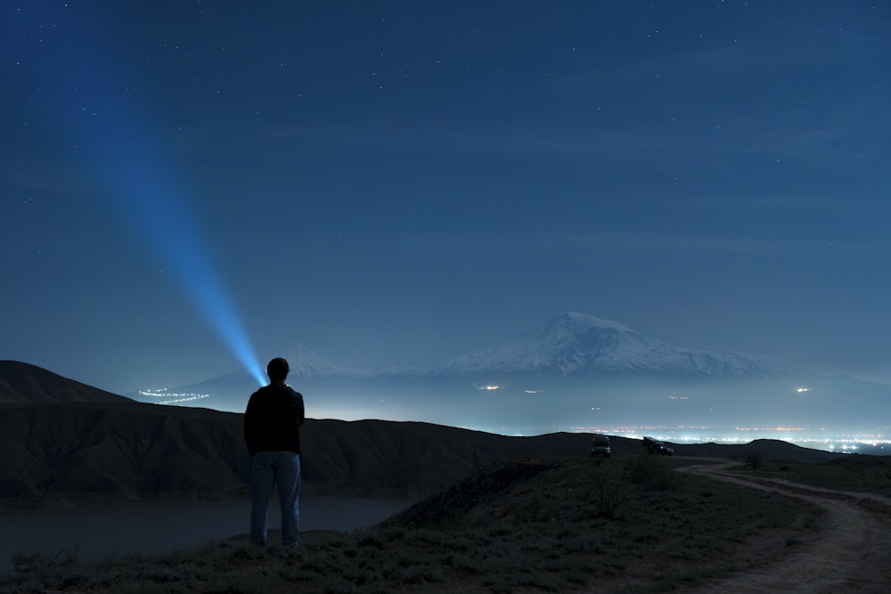 a man standing on top of a dirt road under a sky filled with stars