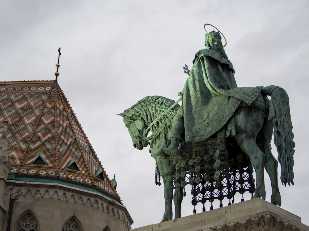 uma estátua de um homem montado em um cavalo ao lado de um edifício