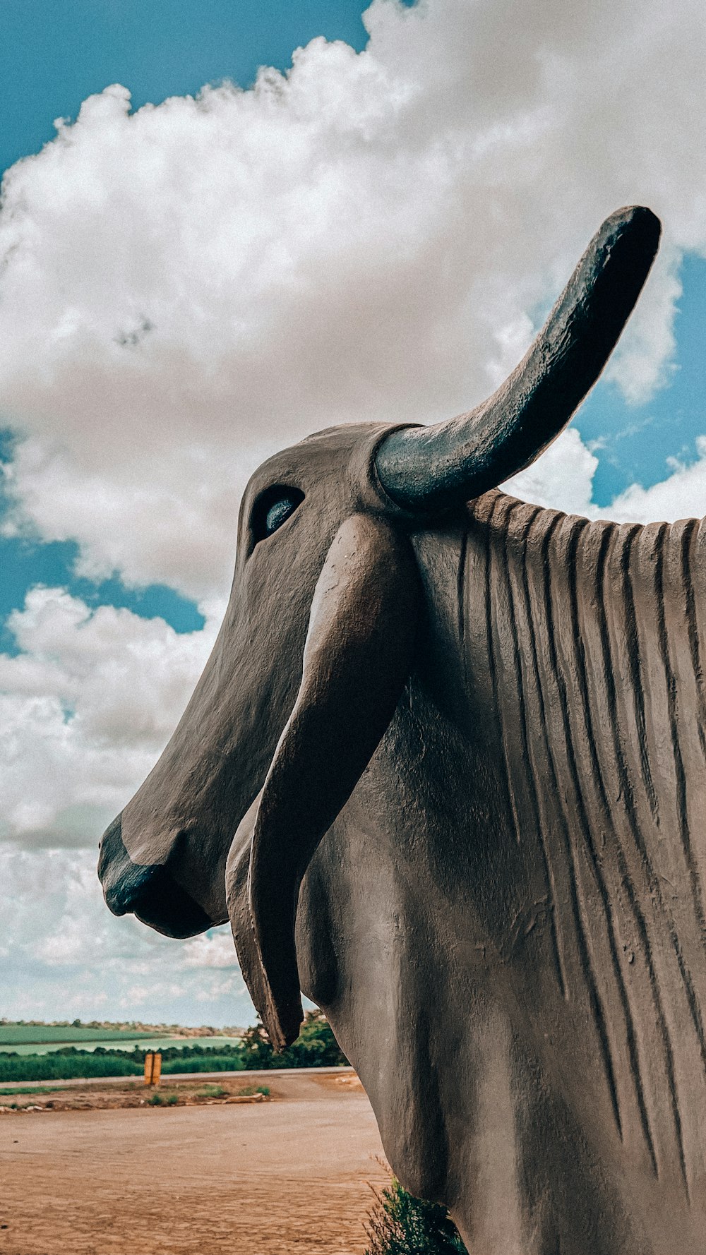 a statue of a cow with a sky background