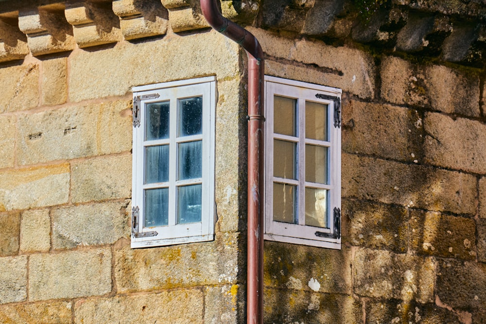 a brick building with two windows and a pipe sticking out of it