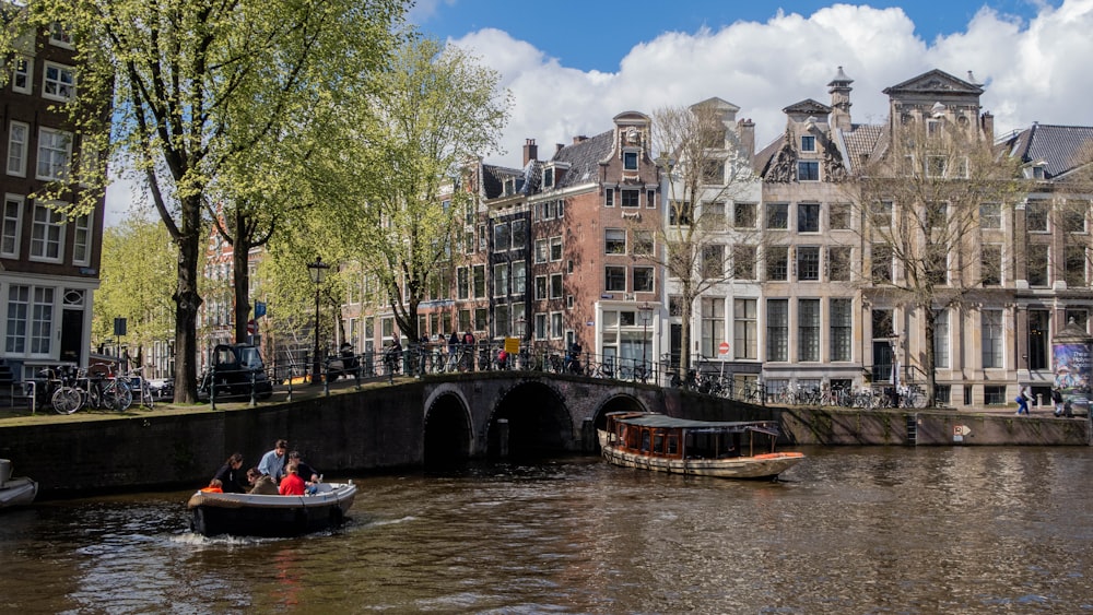 a couple of boats floating down a river next to tall buildings