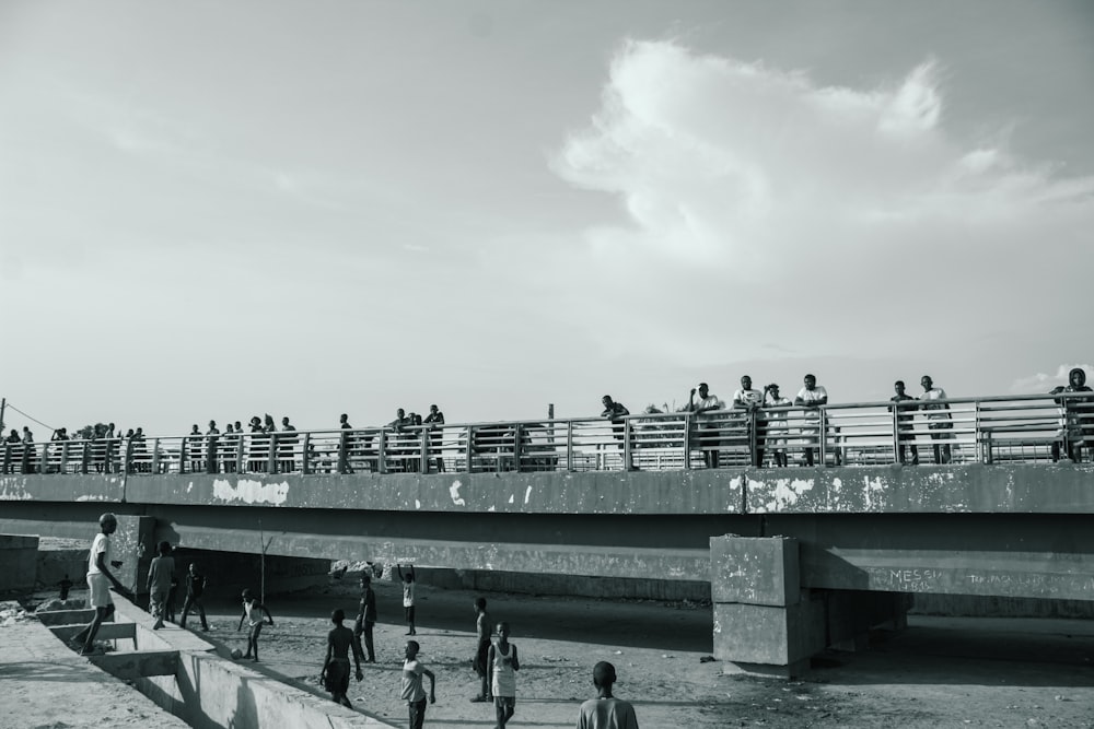 a black and white photo of people walking on a bridge