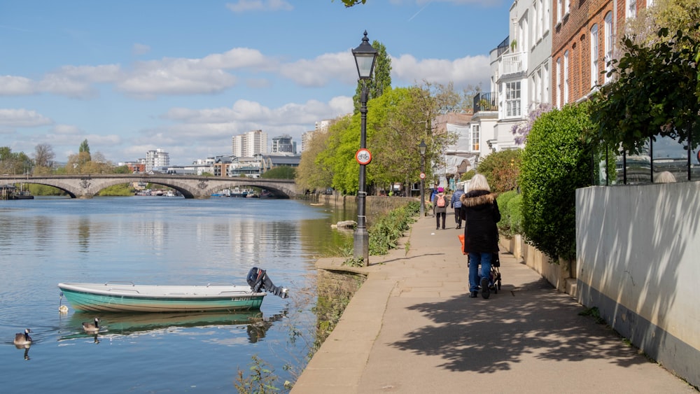 a man walking down a sidewalk next to a river