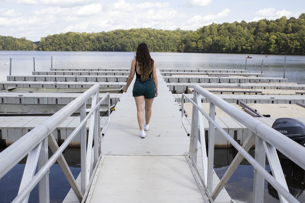 a woman walking down a pier towards a body of water