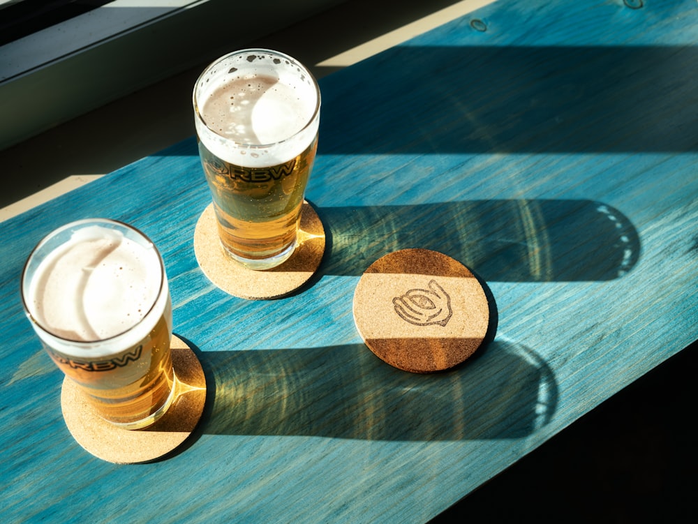 two beer glasses sitting on top of a wooden table