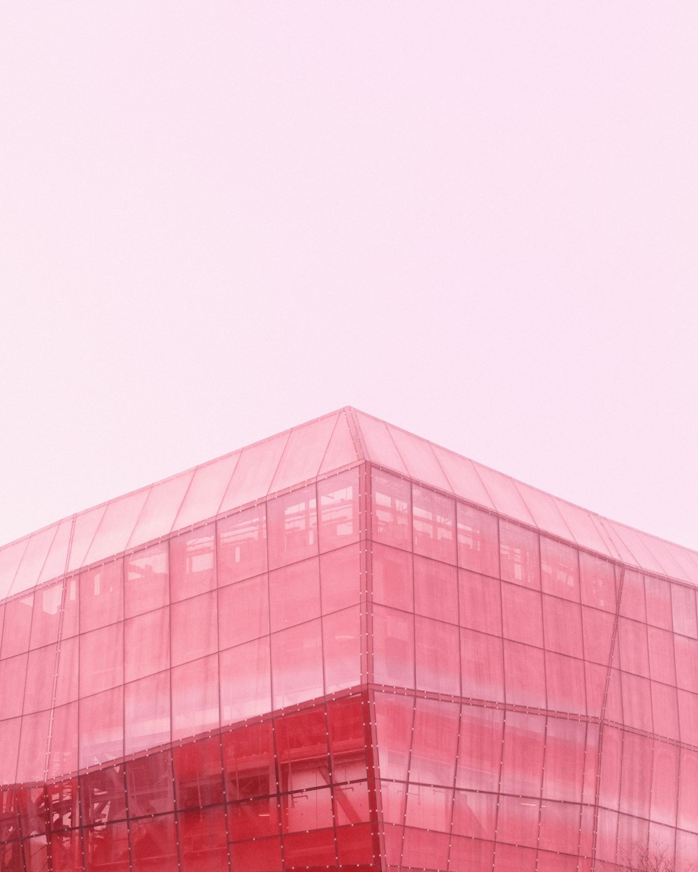  a red glass building with a clock on the top of it