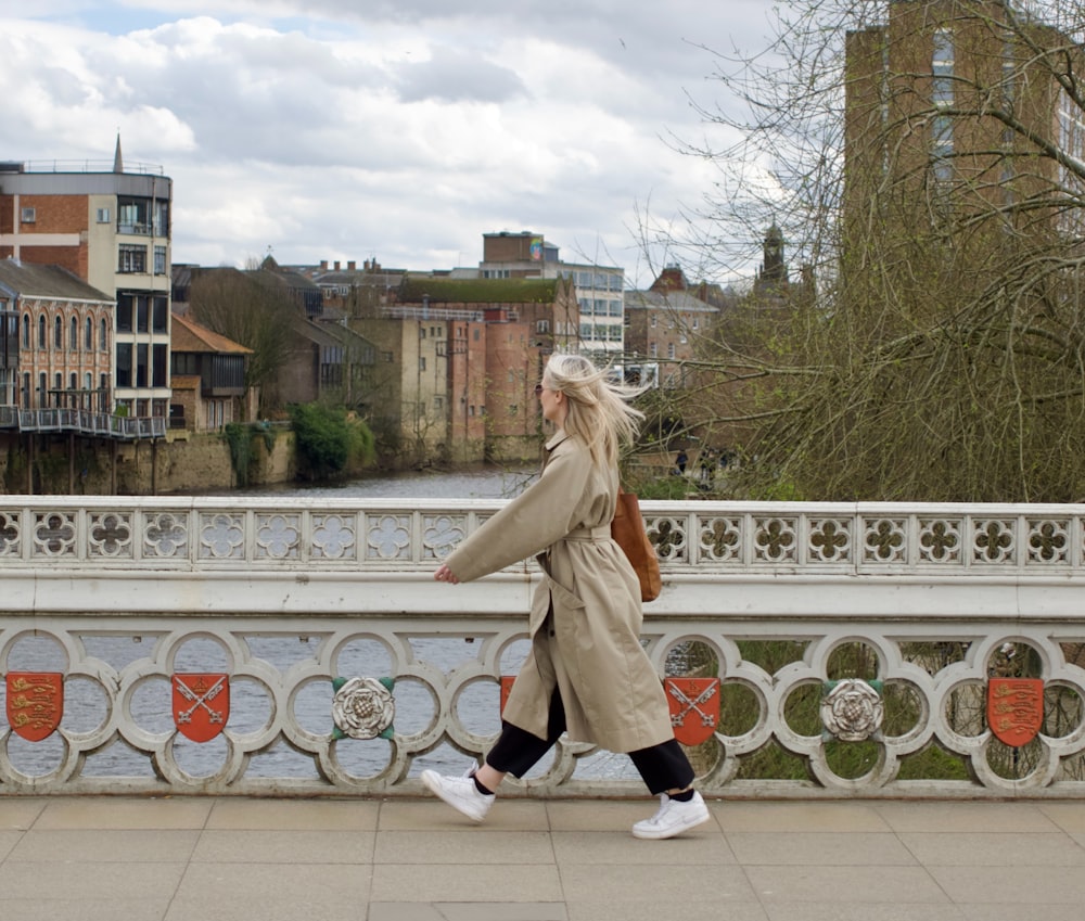 a woman walking across a bridge over a river