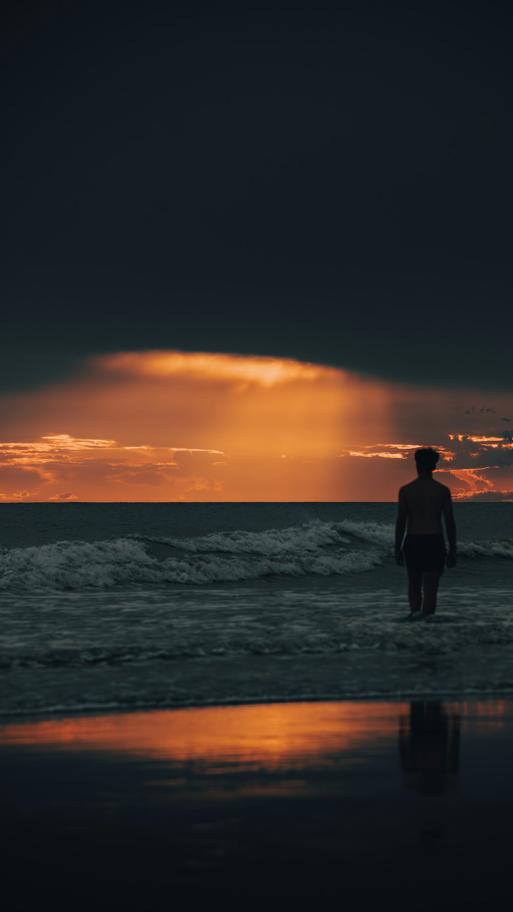 a man standing on top of a beach next to the ocean