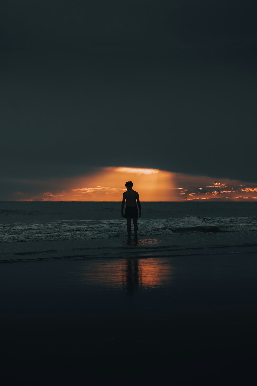 a man standing on the beach at sunset