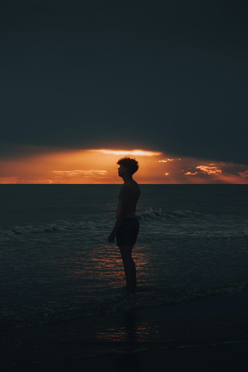 a person standing in the water at sunset