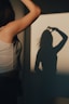 a woman standing in front of a wall with a shadow on it
