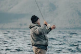a man standing on a boat holding a fishing rod