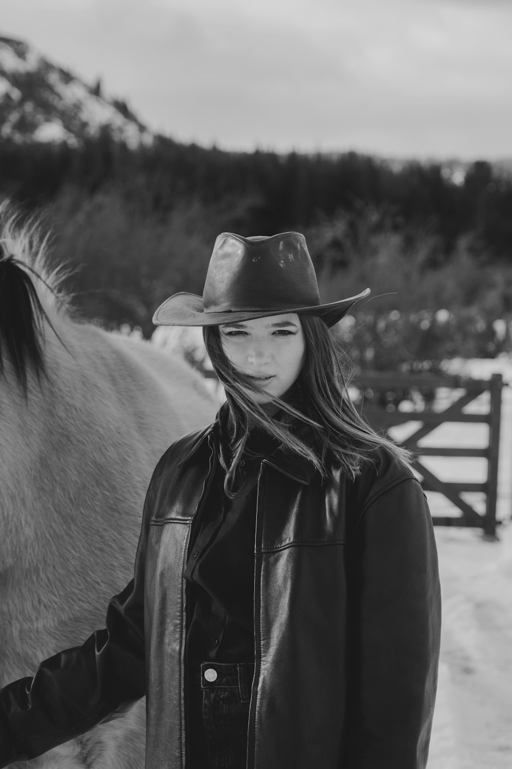 a woman in a cowboy hat standing next to a horse