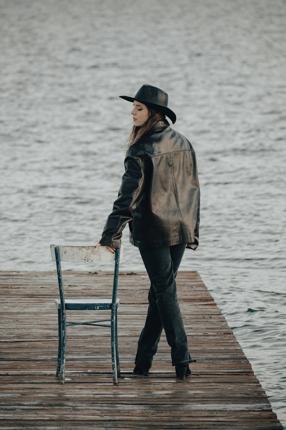 a woman standing on a dock next to a chair
