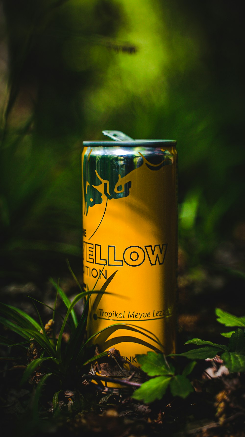a can of yellow on the ground in the grass