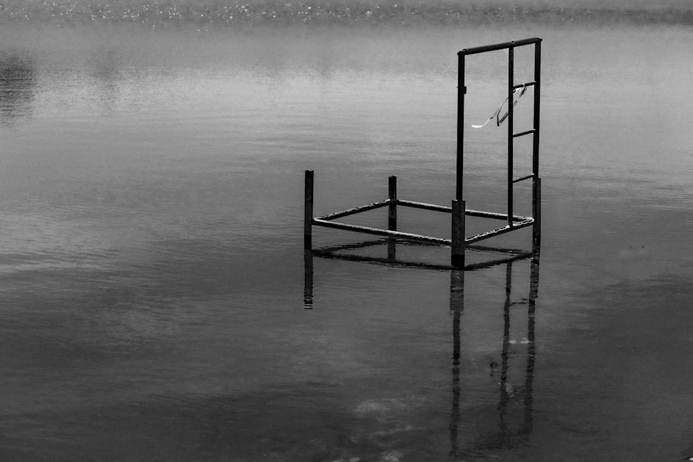 a black and white photo of a chair in the water