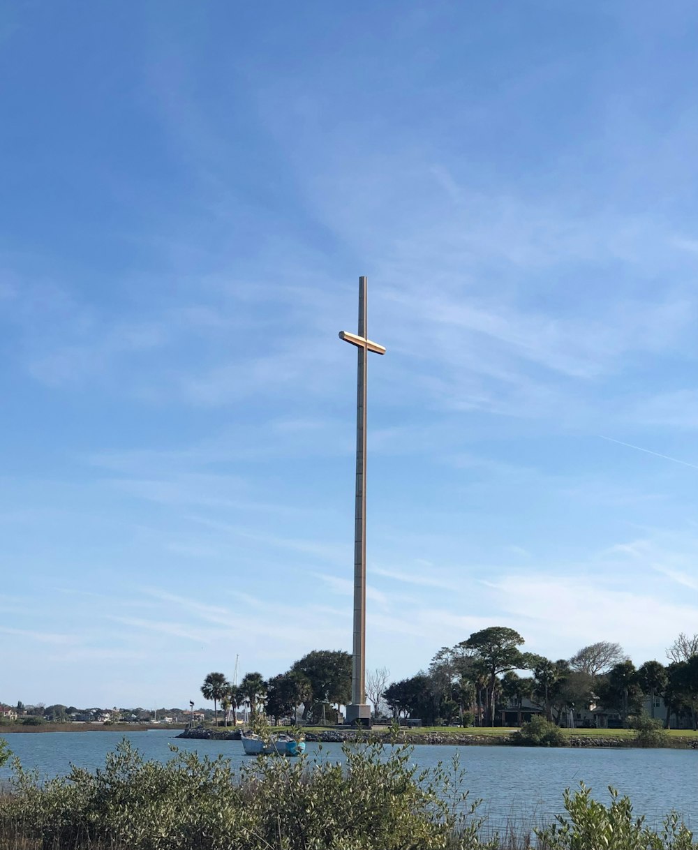 a cross on a pole near a body of water