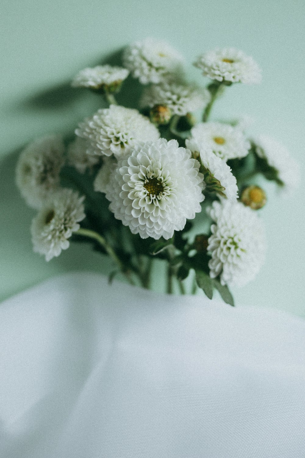 un jarrón lleno de flores blancas encima de una mesa