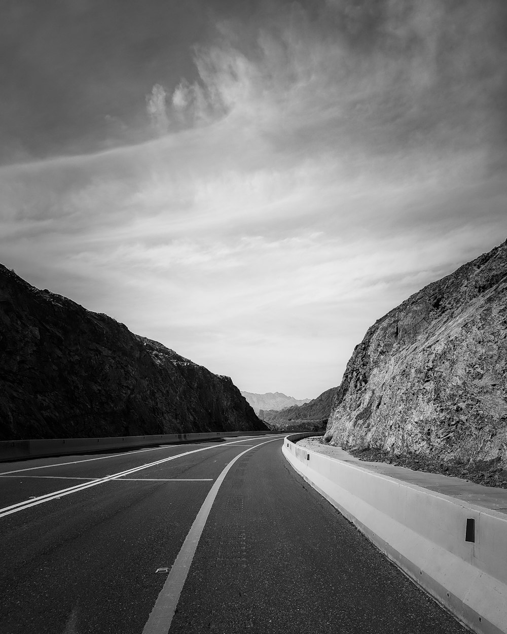 a black and white photo of a mountain road