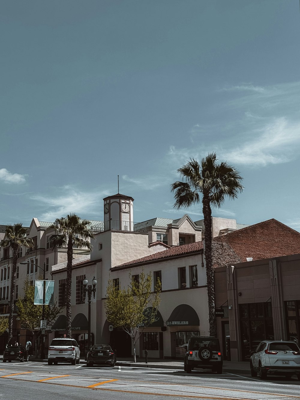 a city street with palm trees and a clock tower