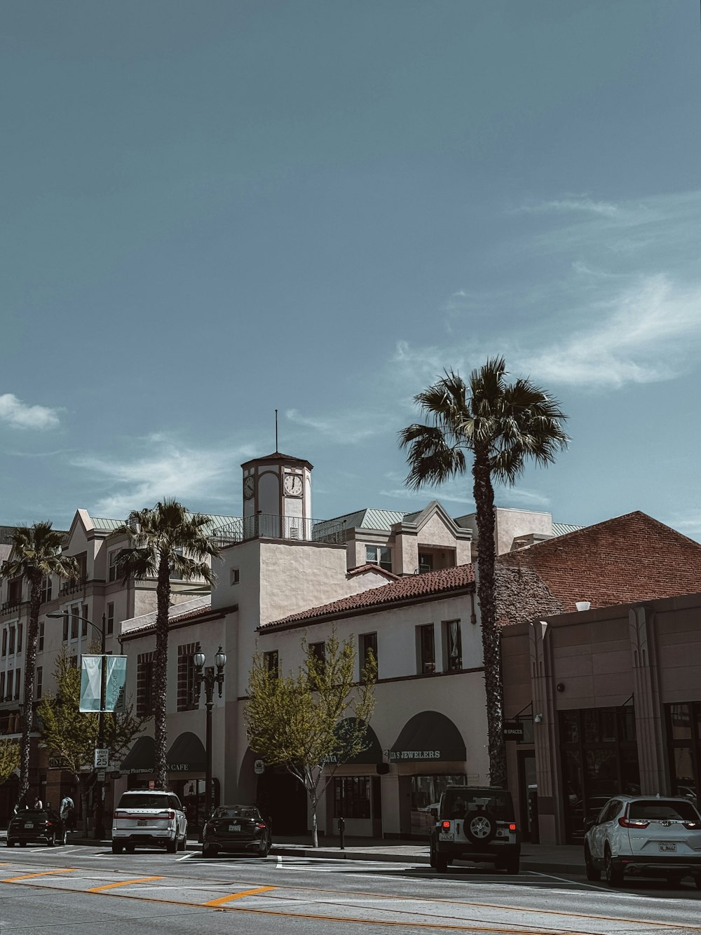 una calle de la ciudad con palmeras y una torre del reloj