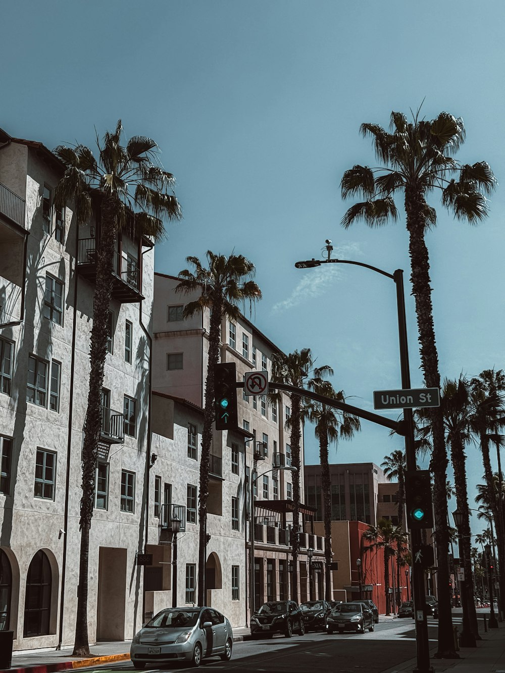 a city street with palm trees and a traffic light