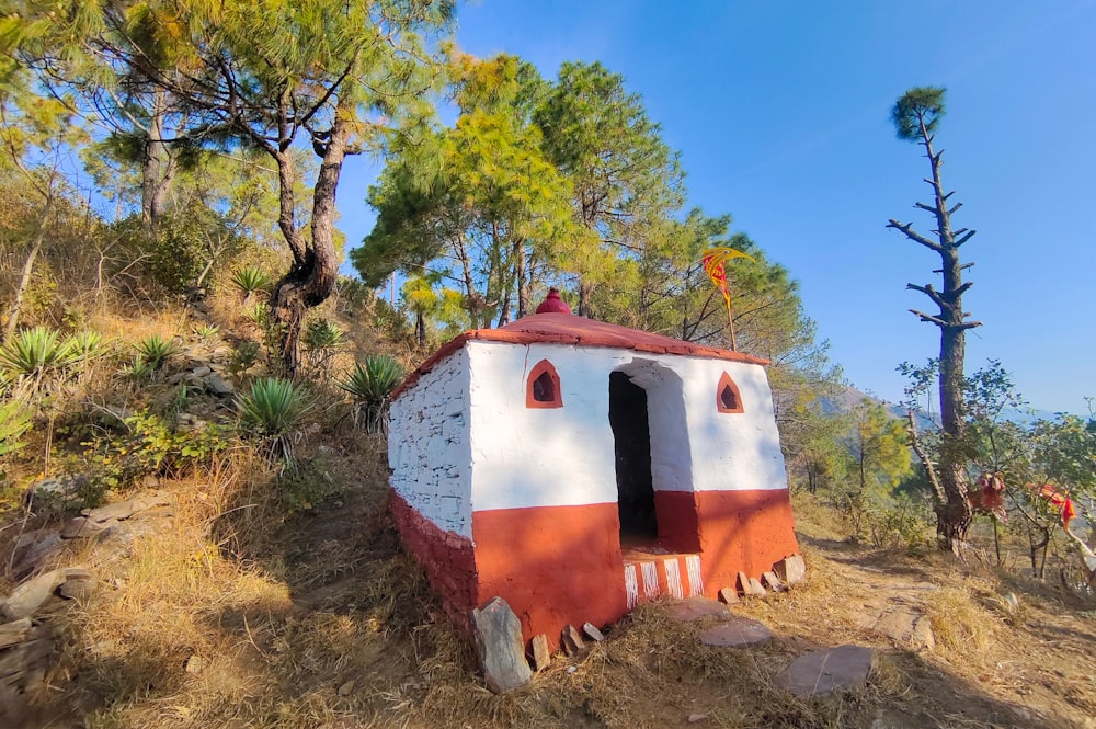a small white and red building sitting on top of a hill