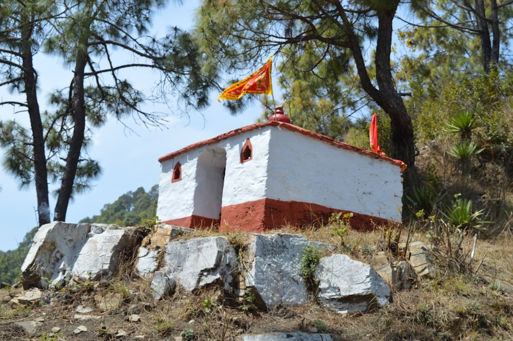 un pequeño edificio blanco y rojo sentado en la cima de una colina