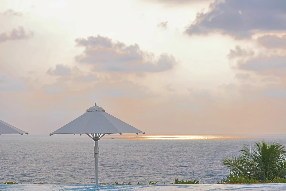 A resort swimming pool with sun loungers at sunset