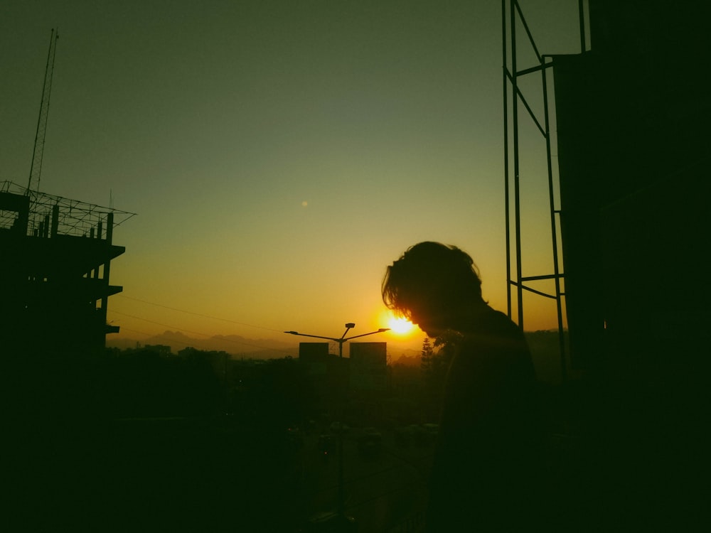 uma pessoa em pé em frente a um prédio ao pôr do sol