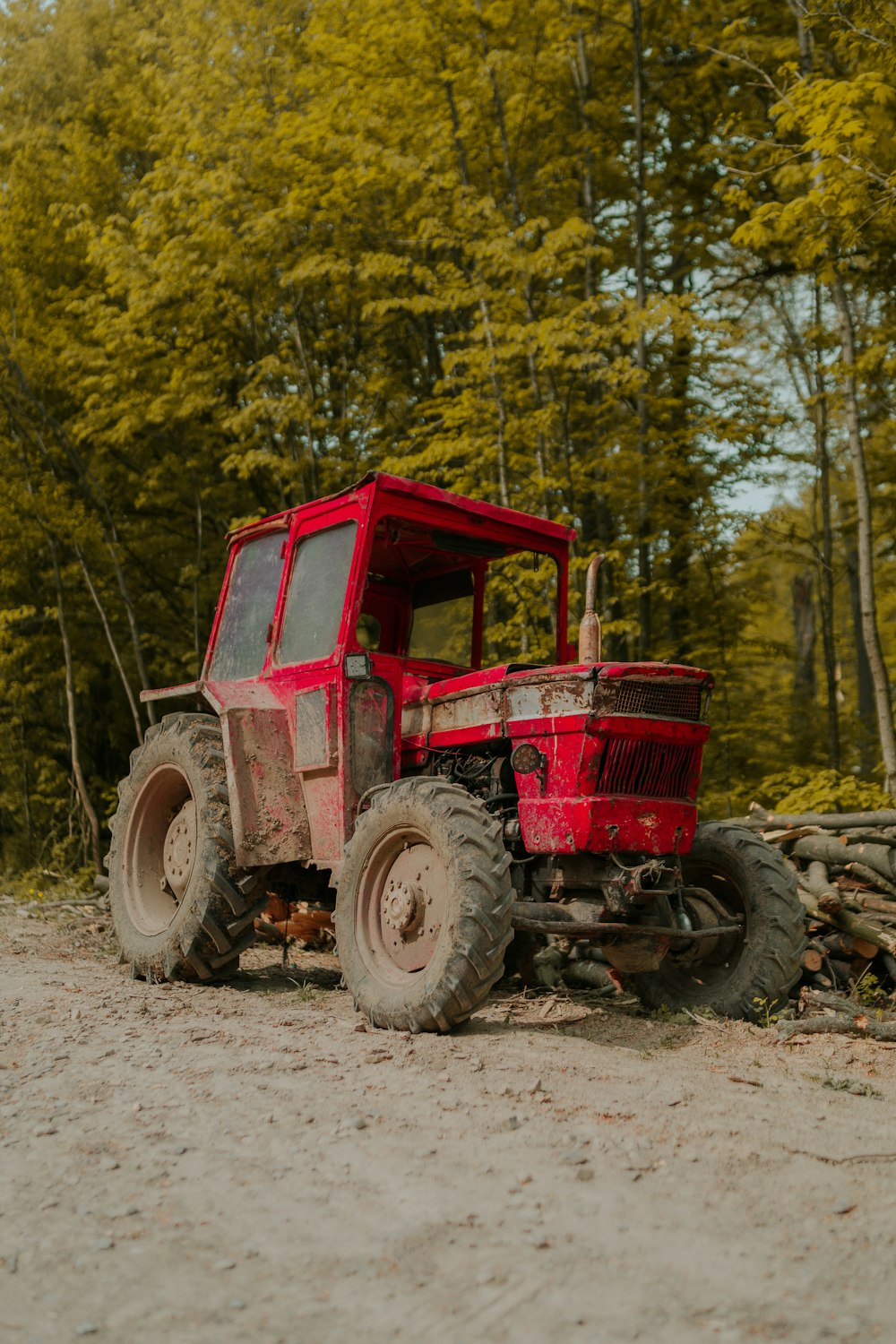 a red tractor parked on top of a dirt road