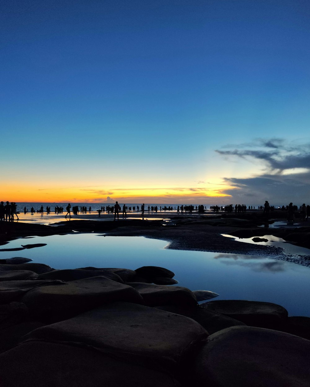a body of water surrounded by rocks at sunset