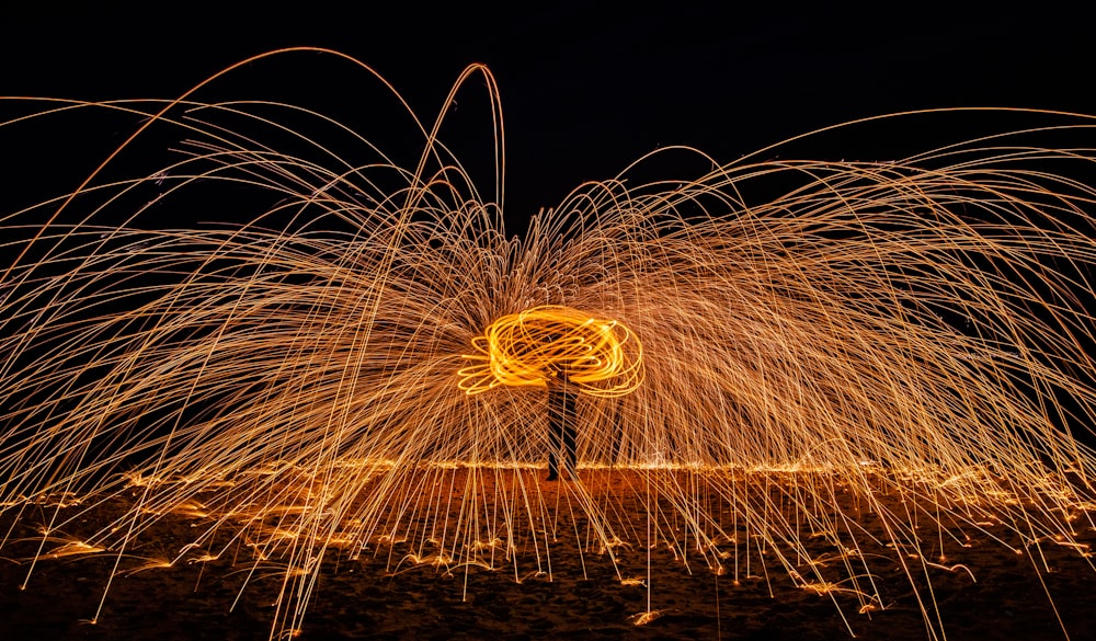 a person standing in the middle of a field with sparks in the air