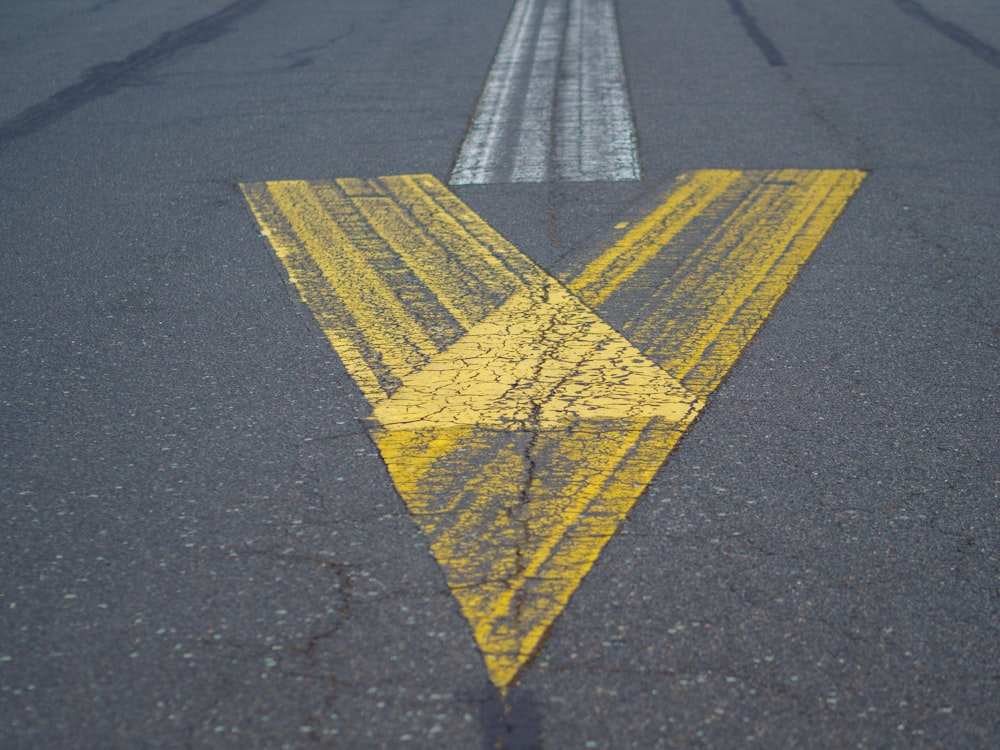 a yellow and white arrow painted on a road