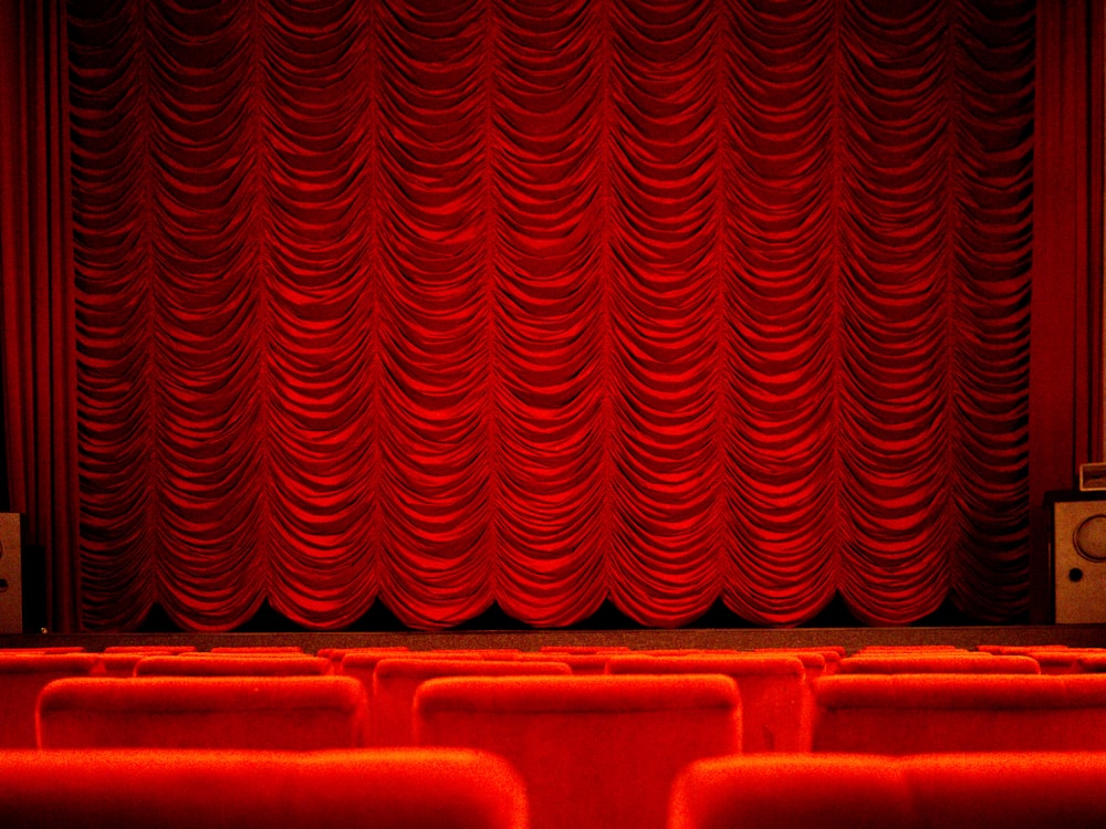 an empty theater with red curtains and seats