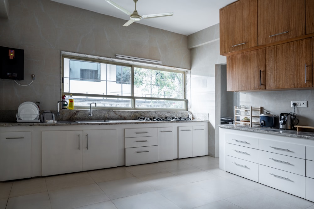 a kitchen with white cabinets and a large window