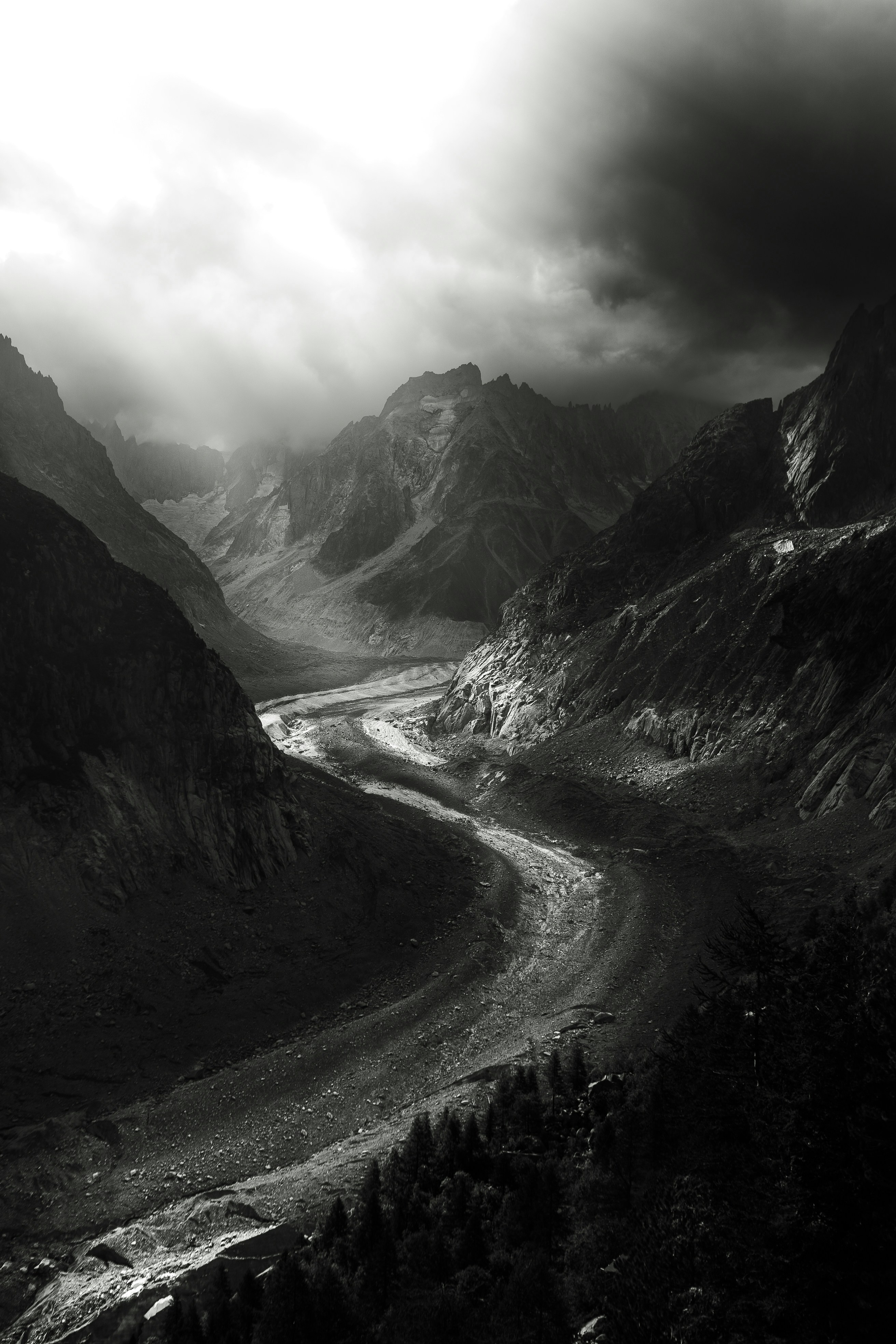 a black and white photo of a river in the mountains