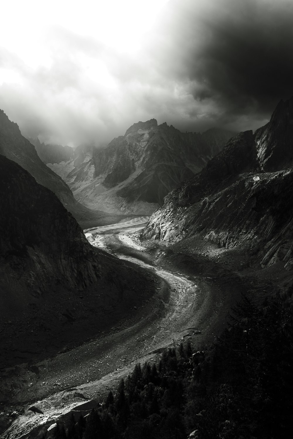 a black and white photo of a river in the mountains