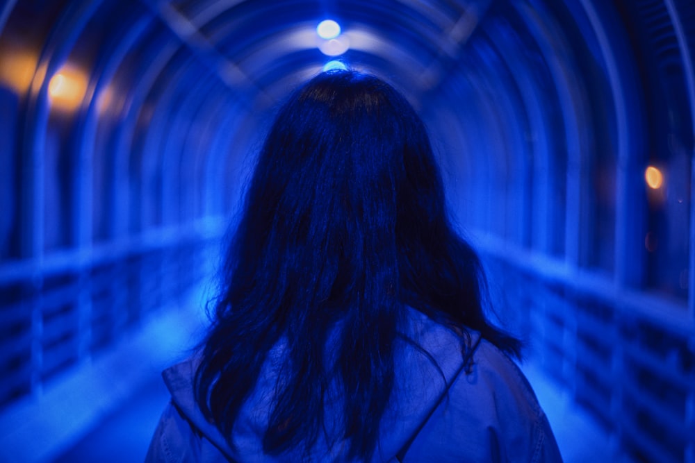 a woman standing in a tunnel with blue lights