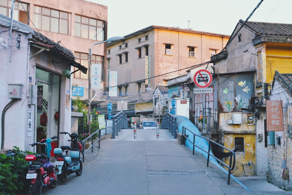 a narrow street lined with buildings and parked scooters