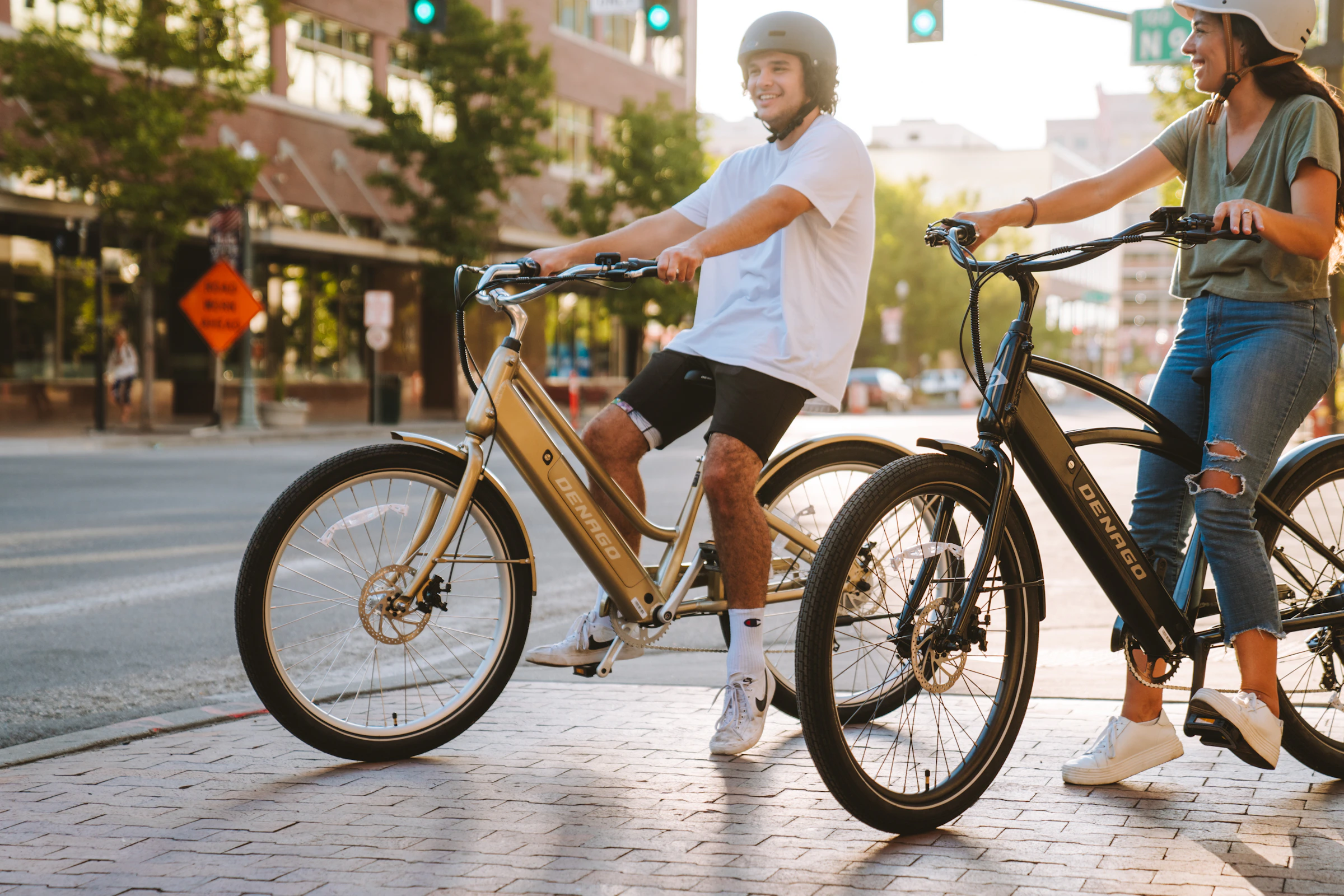 Two helmeted cyclists with bicycles on a city street