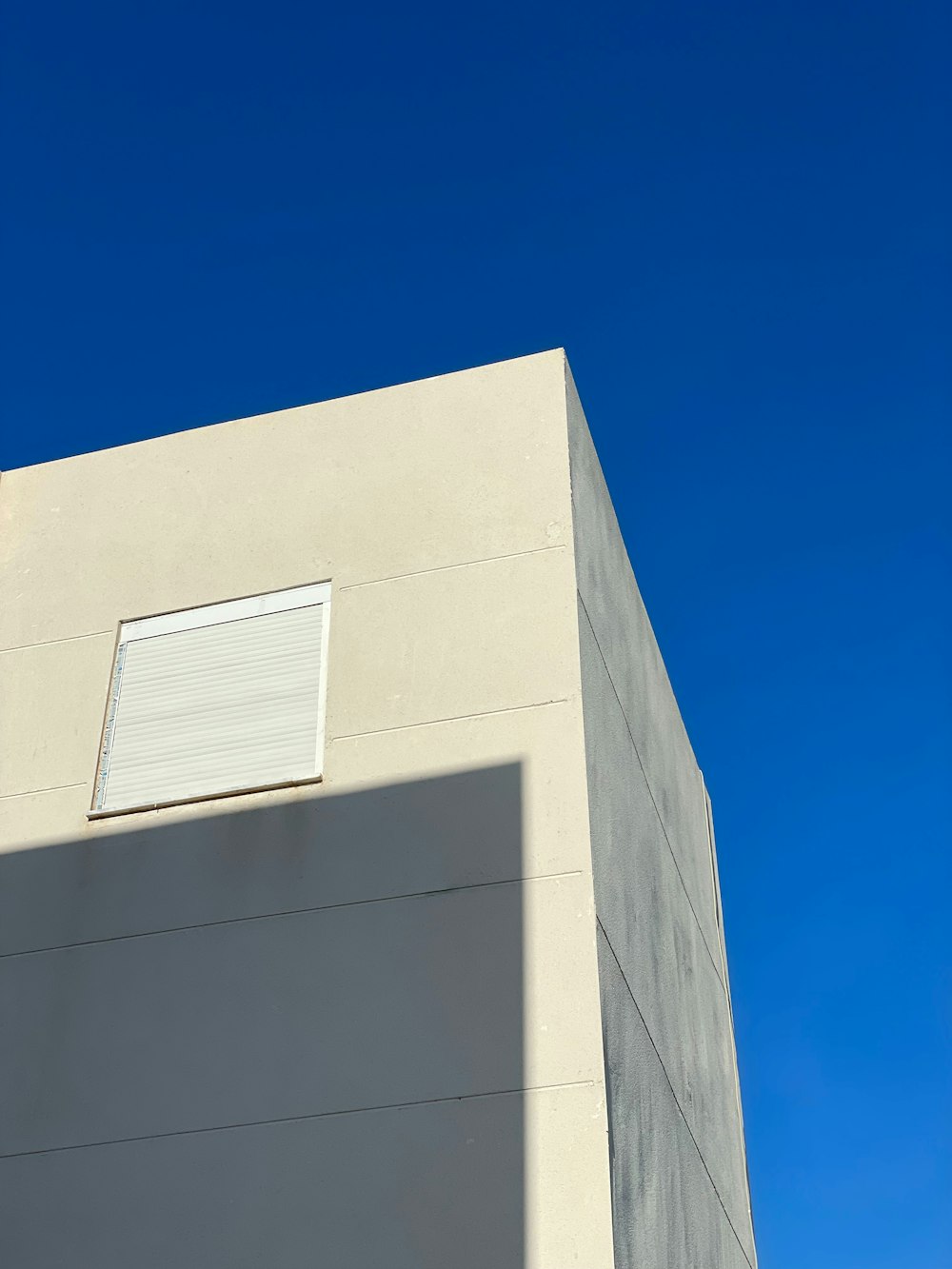 a white building with a window and a sky background