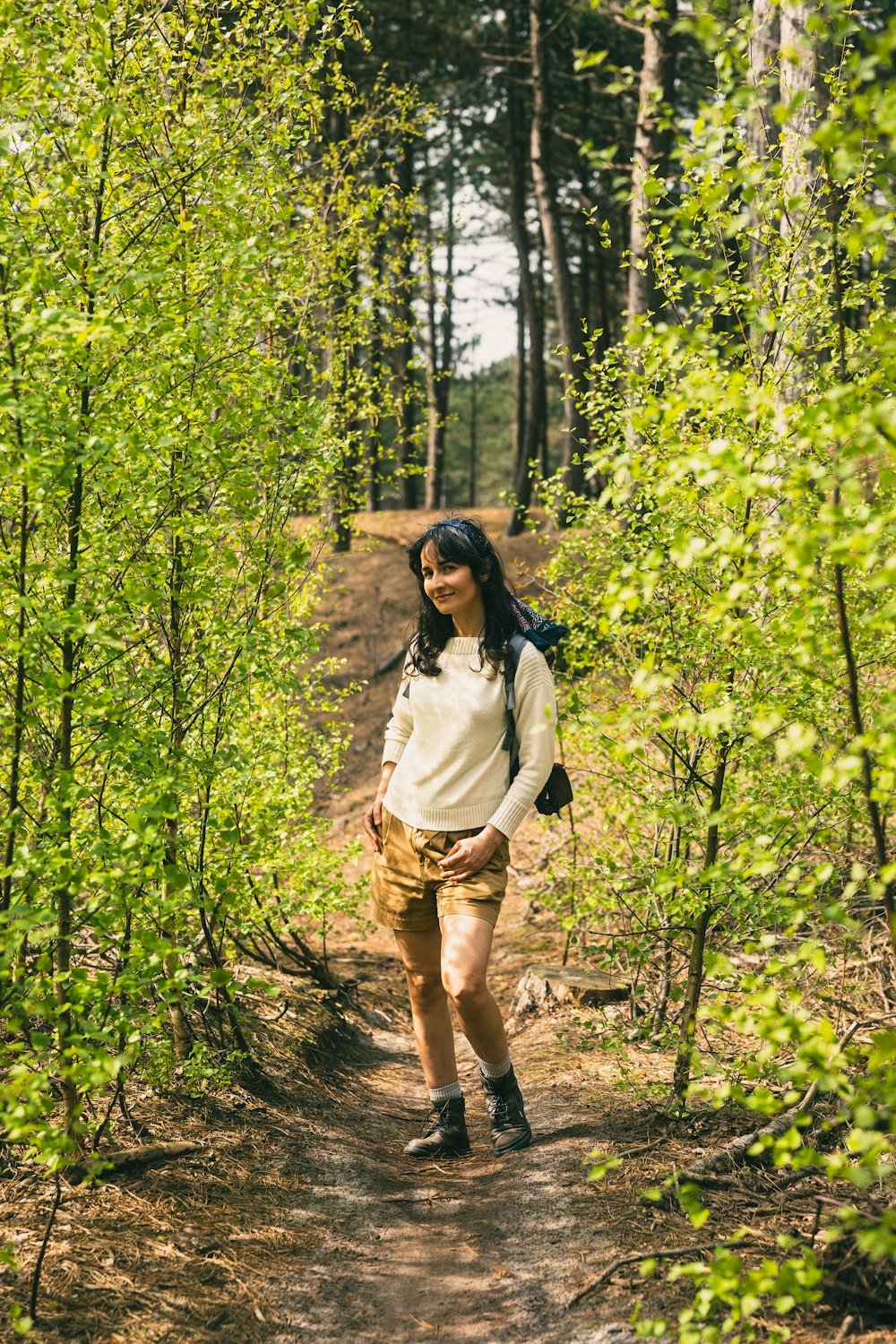 a woman with a backpack is walking through the woods
