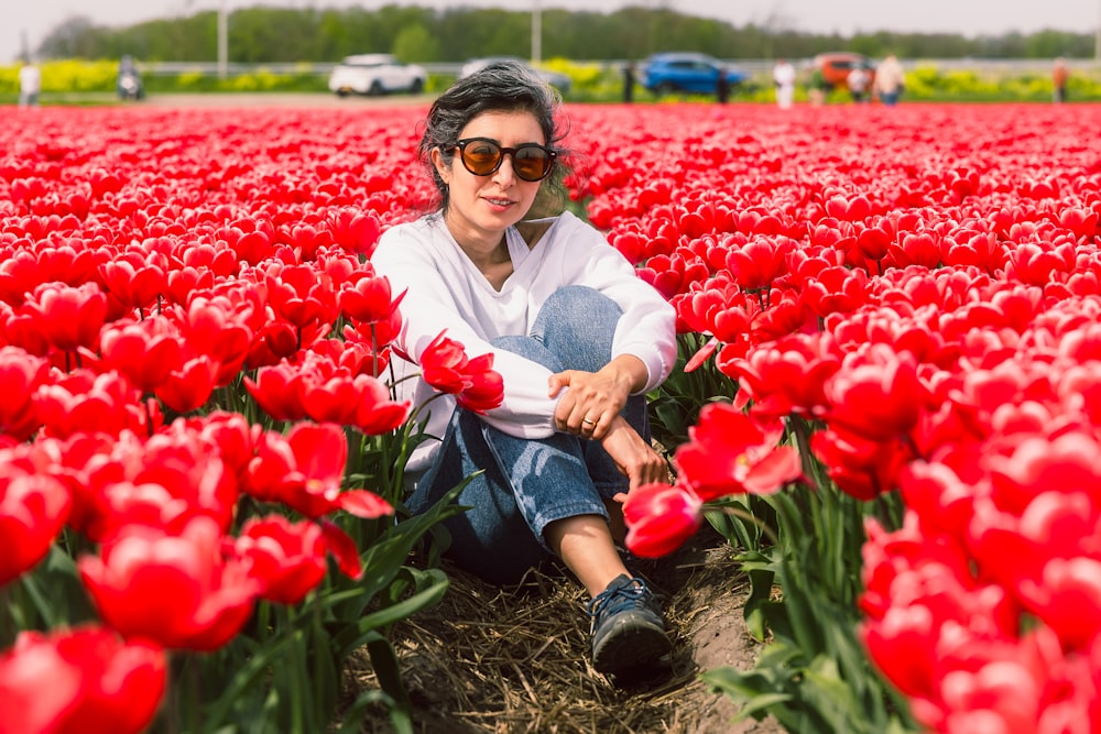 a woman sitting in a field of red tulips